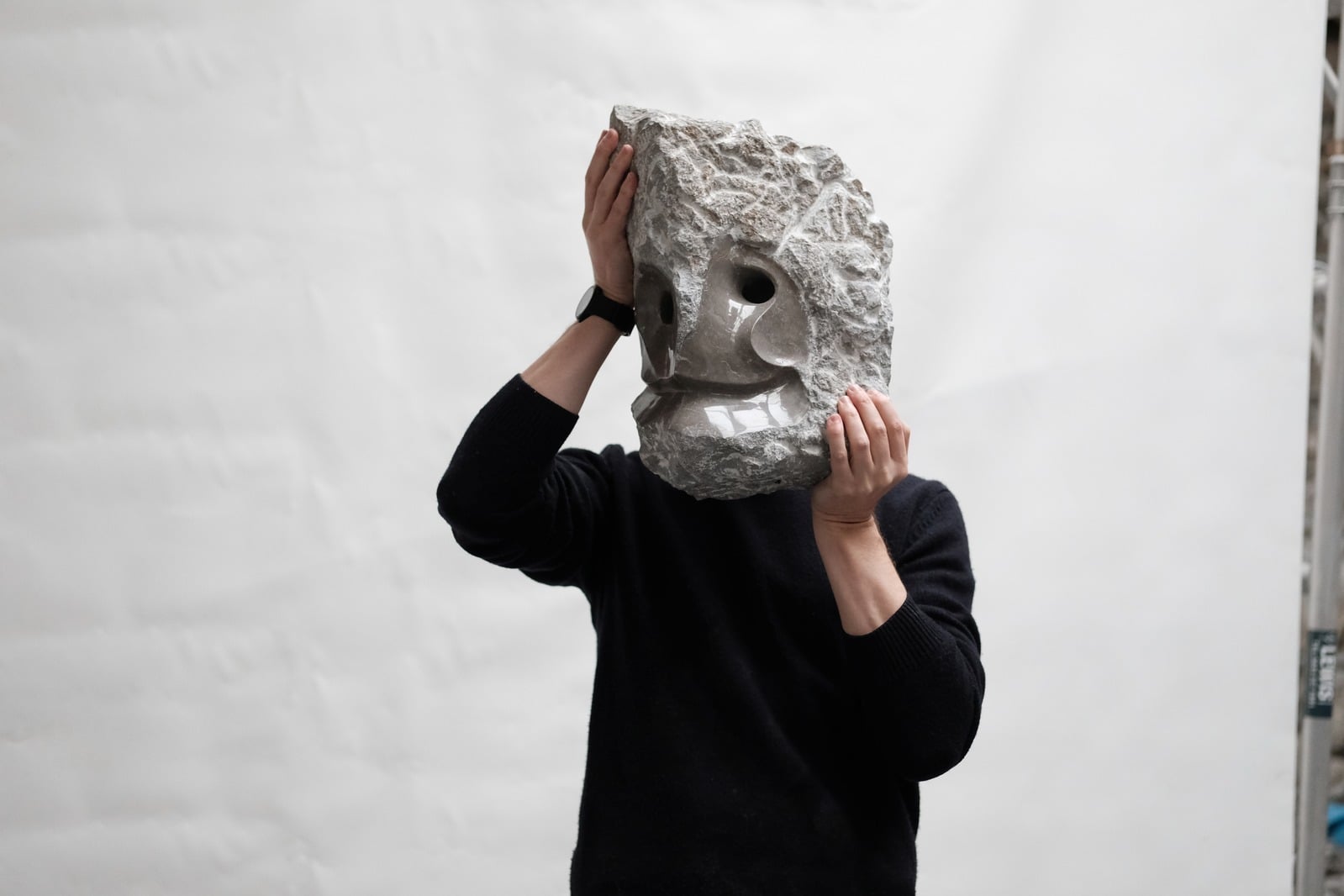James Stephenson holding his limestone sculpture KAIROS in front of his face