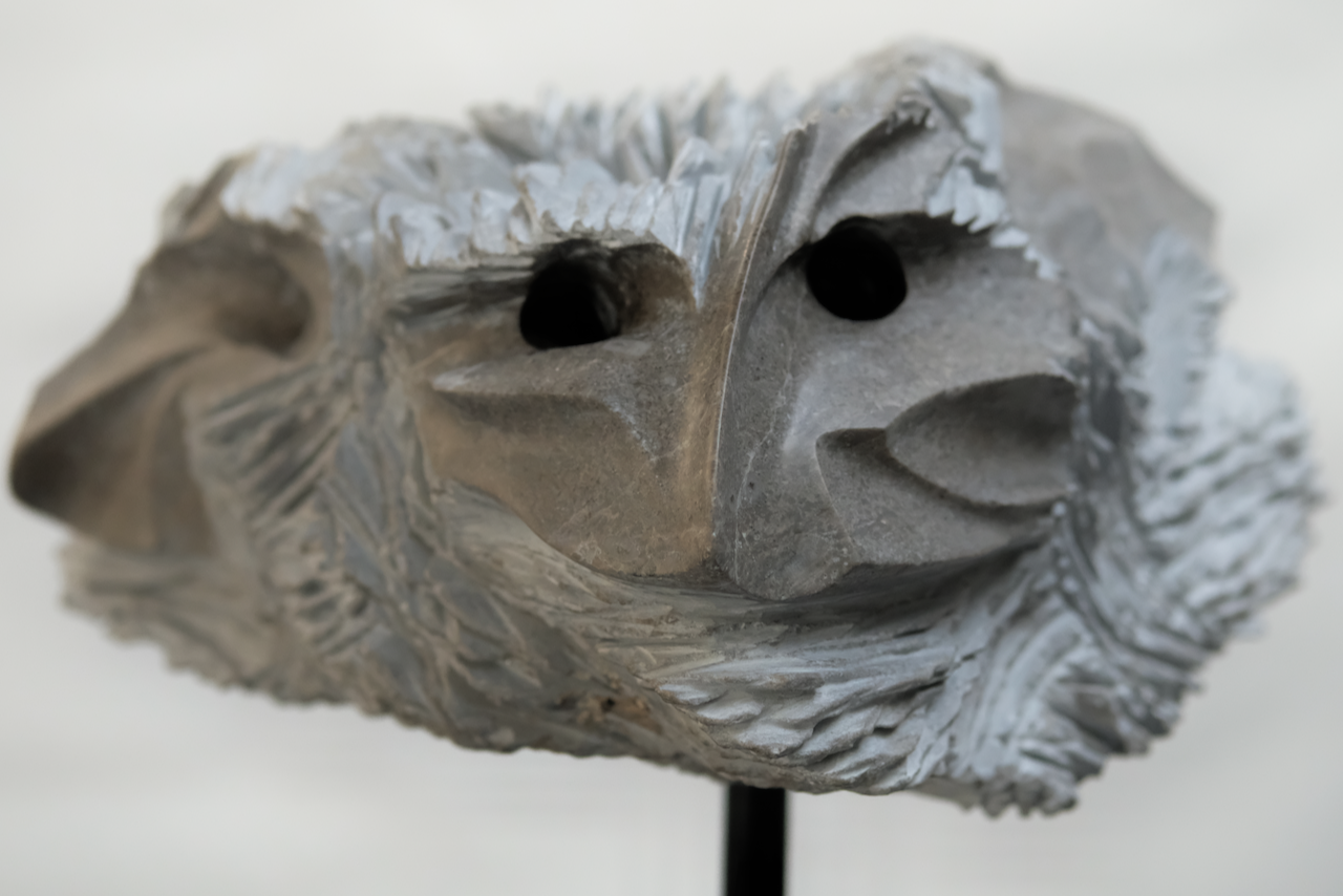 NORNIS, a broad limestone sculpture with multiple abstracted faces and carved apertures
